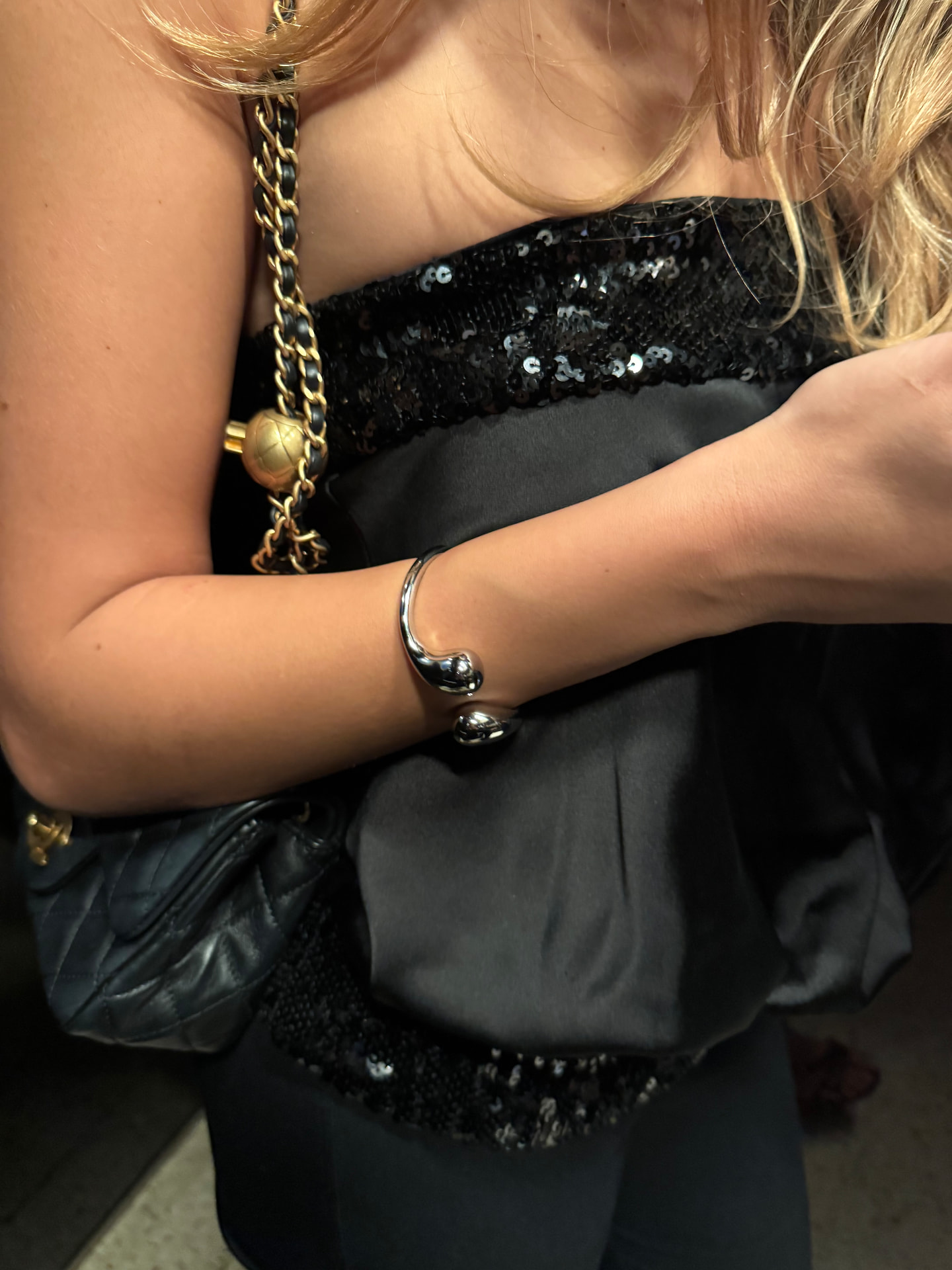Bracciale argentato aperto indossato con un abito nero